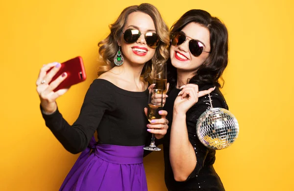 Zwei Mädchen mit einem Glas Wein und Discokugeln, machen Selfie, freuen sich und lächeln. — Stockfoto