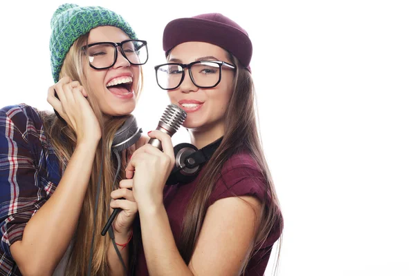 Deux jeunes amies debout ensemble et écoutant de la musique et chantant — Photo
