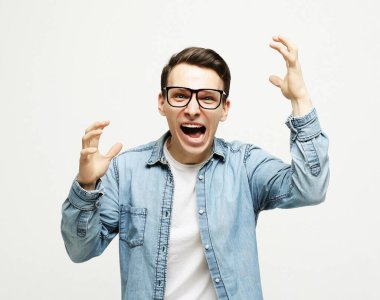 Mutlu genç yakışıklı adam el kol hareketi yapıyor ve ağzını kapalı tutuyor.