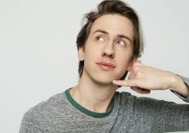 Genç çekici adam telefon işareti yapıyor.