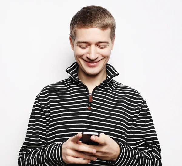 Feliz joven en gafas escribiendo sms sobre fondo blanco — Foto de Stock