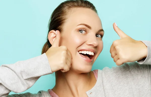 Happy young caucasian female making thumb up sign and smiling cheerfully