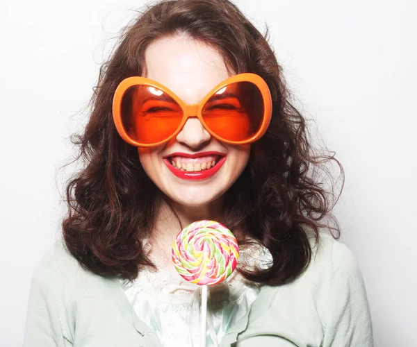 Mujer en grandes gafas de color naranja lamiendo piruleta con su lengua —  Fotos de Stock