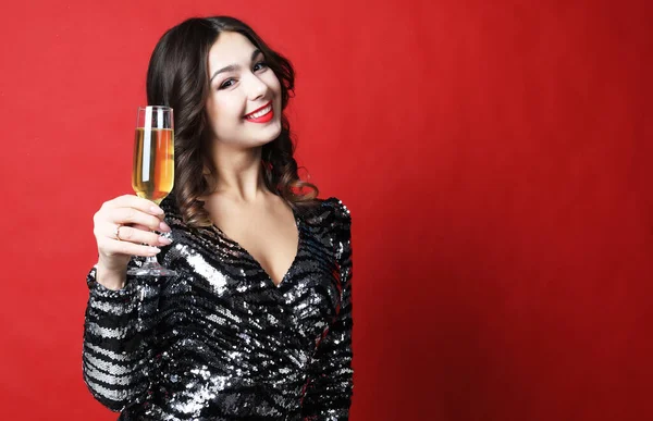 Siyah elbiseli kadın kırmızı arka planda bir kadeh şampanya tutuyor. — Stok fotoğraf