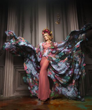 Çiçek renginde bir elbise giymiş güzel sarışın bir kadın. Çelenk desenli.