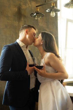 Genç evli çift şarap içip mutluluklarına, romantizmlerine ve şefkatlerine gülümsüyor.