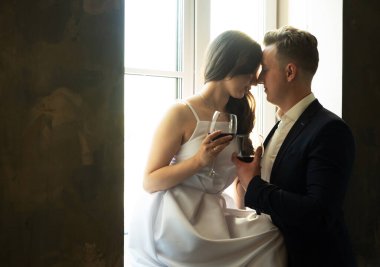 Genç evli çift şarap içip mutluluklarına, romantizmlerine ve şefkatlerine gülümsüyor.