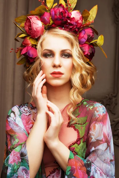 Hermosa mujer rubia en un vestido de colores florales con corona de flores —  Fotos de Stock