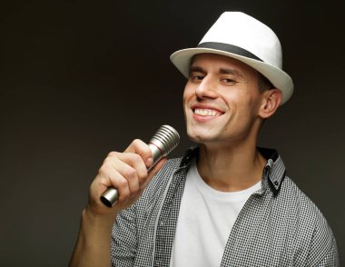 Karaoke zamanı. Genç adam mikrofonla şarkı söylüyor.