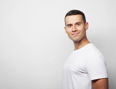 Mutlu adam beyaz arka planda kameraya bakıyor.