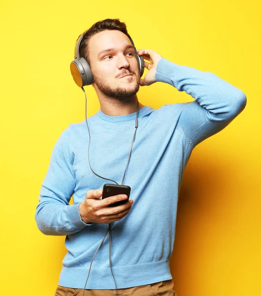 Knappe man likken aan muziek over gele achtergrond — Stockfoto