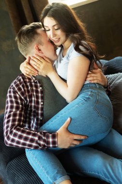 Genç ve güzel bir çift kanepede oturuyor ve sarılıyorlar. Mutlu aile hayatı.