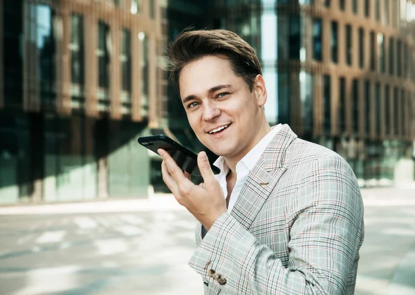 Concepto de negocio, tecnología y personas - joven empresario con smartphone sobre edificio de oficinas —  Fotos de Stock