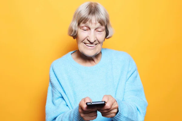 Stará žena v modrém svetru mluví na mobilu — Stock fotografie
