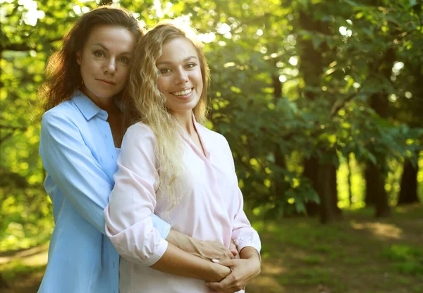 Lifestyle and people concept: mature mother and adult daughter hugging in the park on a summer day — Stock Photo, Image