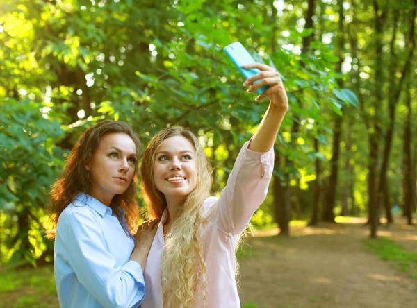 Зріла мати і доросла дочка роблять селфі на мобільному телефоні в літньому парку — стокове фото