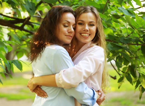 Estilo de vida e conceito de pessoas: mãe madura e filha adulta abraçando no parque em um dia de verão — Fotografia de Stock