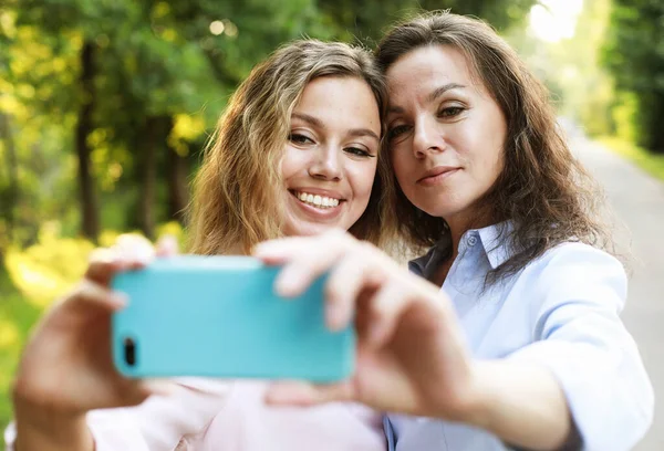 Maduro mãe e filha adulta estão fazendo selfie por telefone celular no parque de verão — Fotografia de Stock