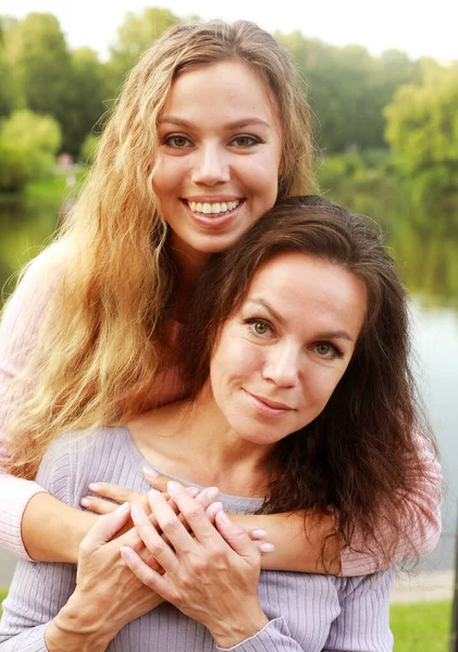 Lifestyle en people concept: volwassen moeder en volwassen dochter knuffelen in het park op een zomerdag — Stockfoto