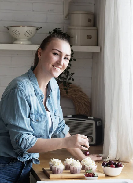 young woman pastry chef decorates cupcakes