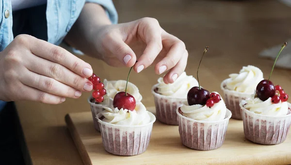 Giovane pasticcere donna decora cupcakes — Foto Stock