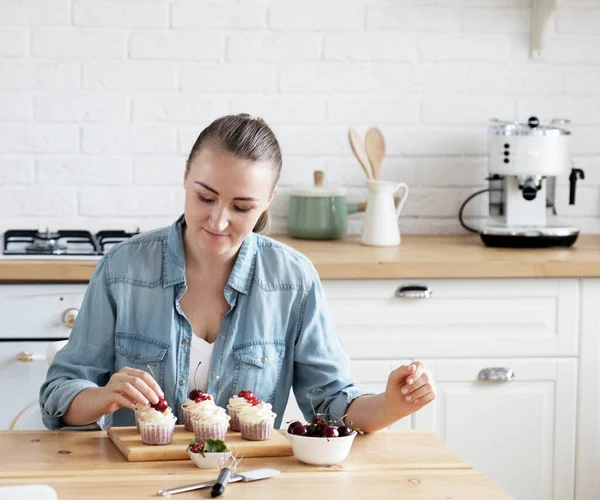 Young woman pastry chef decorates cupcakes — Stock Photo, Image