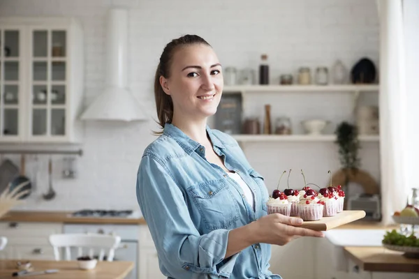 Young baker woman holding cupcakes. Happy, smiling and cheerful. — Stock Photo, Image