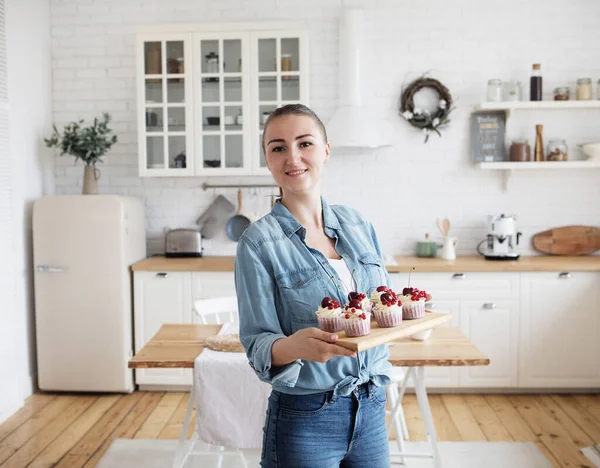 Egy fiatal pék nő sütit tart. Boldog, mosolygós és vidám.. — Stock Fotó