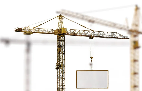 Yellow hoisting crane with advertisement hoardin — Stock Photo, Image