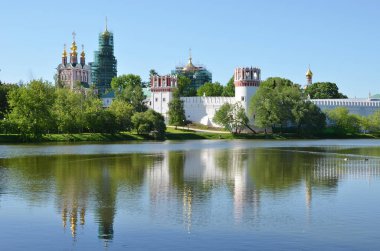 Novodevichiy Convent in green of trees by river under blue sky, Moscow clipart