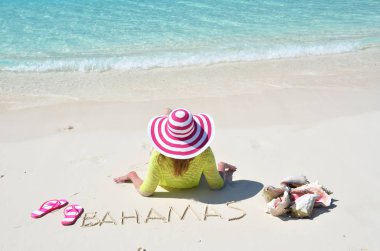 Güneş-şapkalı genç kadının fotoğrafını rahatla Great Exuma, Bahamas metin ile kum plajındaki