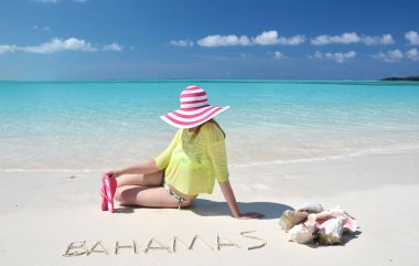 Güneş-şapkalı genç kadının fotoğrafını rahatla Great Exuma, Bahamas metin ile kum plajındaki