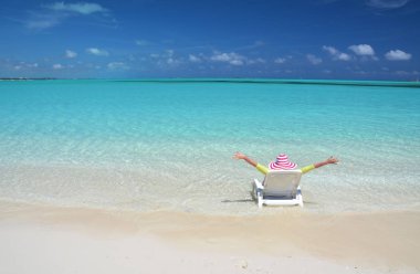 Genç kadın güneş-şapkalı relax şezlong üzerinde kumlu plaj Great Exuma, Bahamas içinde