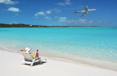 Güneş-şapkalı genç kadının fotoğrafını rahatla üzerinde kumlu plaj, Great Exuma, Bahamas mavi gökyüzünde uçak ile