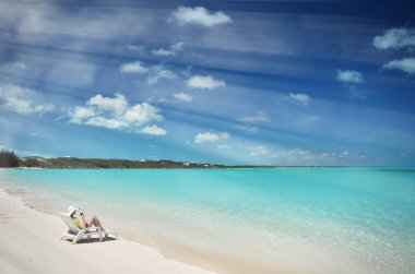 Genç kadın güneş-şapkalı relax şezlong üzerinde kumlu plaj Great Exuma, Bahamas içinde