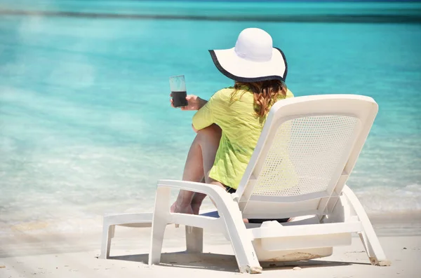 young woman in sun-hat relax in sunbed on sandy beach of Great Exuma, Bahamas