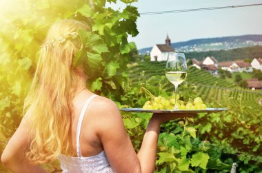 Woman hiding face in grape leaves and holding wine and grapes on tray, Rheinau, Switzerland clipart