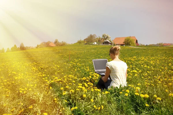 春の牧草地にノートブック コンピューターを持つ少女 — ストック写真