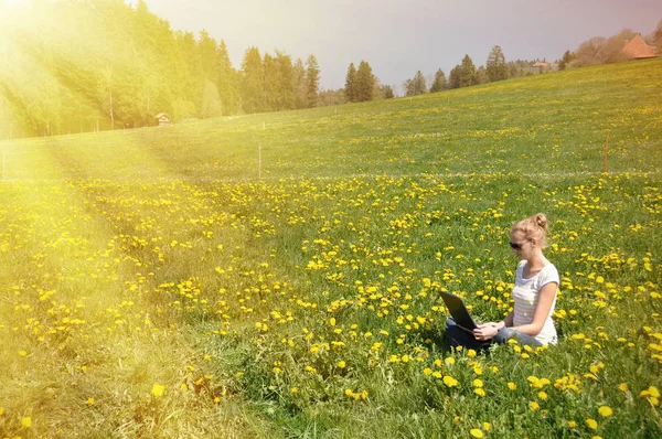 Gadis dengan komputer notebook di padang rumput musim semi — Stok Foto