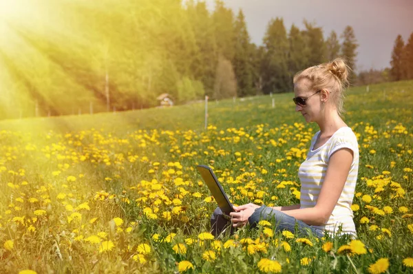 春の牧草地にノートブック コンピューターを持つ少女 — ストック写真