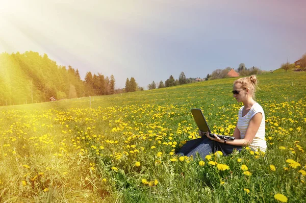 Fille avec un ordinateur portable sur la prairie de printemps — Photo