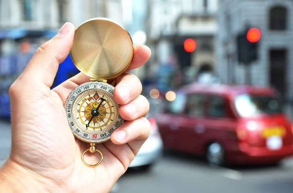 Kompas in de hand tegen een stadsstraat — Stockfoto