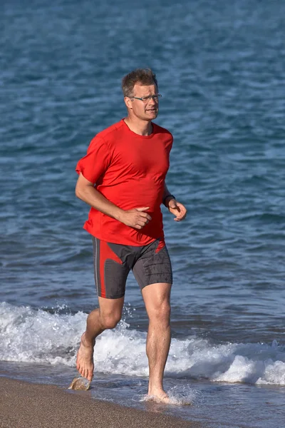春天在西班牙海滩上穿着红色 T恤跑步的年轻跑步者 — 图库照片