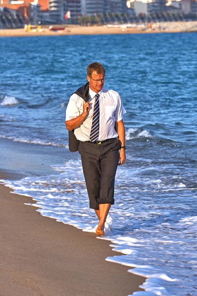在西班牙布拉瓦海岸的水中走在沙滩上的年轻商人 — 图库照片