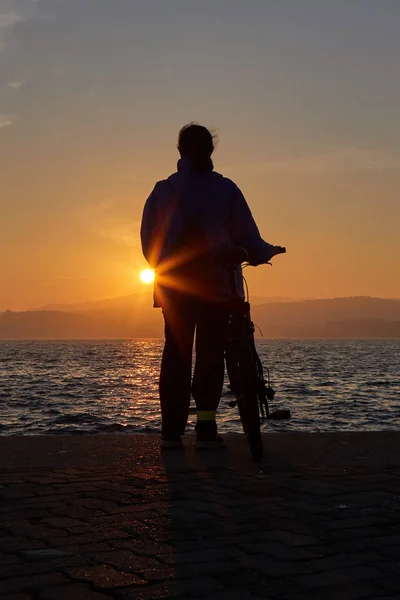 Silueta de niña bonita con bicicleta en una luz del atardecer —  Fotos de Stock