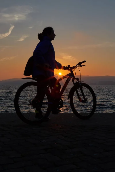 Mooi meisje silhouet met fiets in een zonsondergang licht — Stockfoto