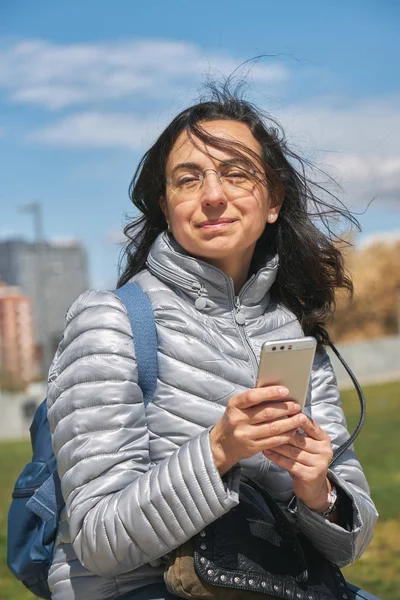 Красива жінка з мобільним телефоном в сонячний день на відкритому повітрі Ліцензійні Стокові Зображення