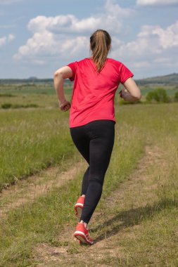 Genç güzel kız çayırda koşuyor.
