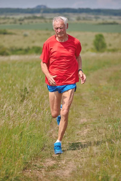 Senior runner running on the meadow at springtime — Stock Photo, Image