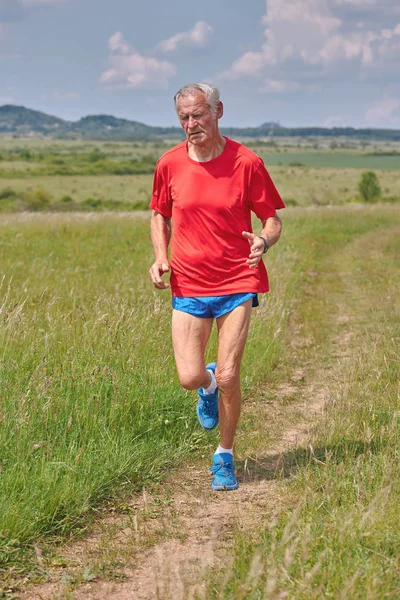 Senior runner running on the meadow at springtime — Stock Photo, Image